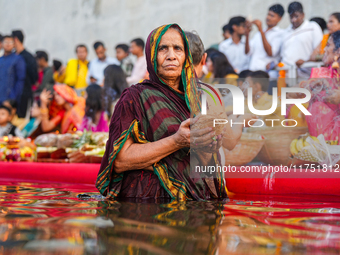 Hindu devotees perform rituals and offer prayers at sunset on the banks of the River Sabarmati during the Chhath Puja festival in Ahmedabad,...