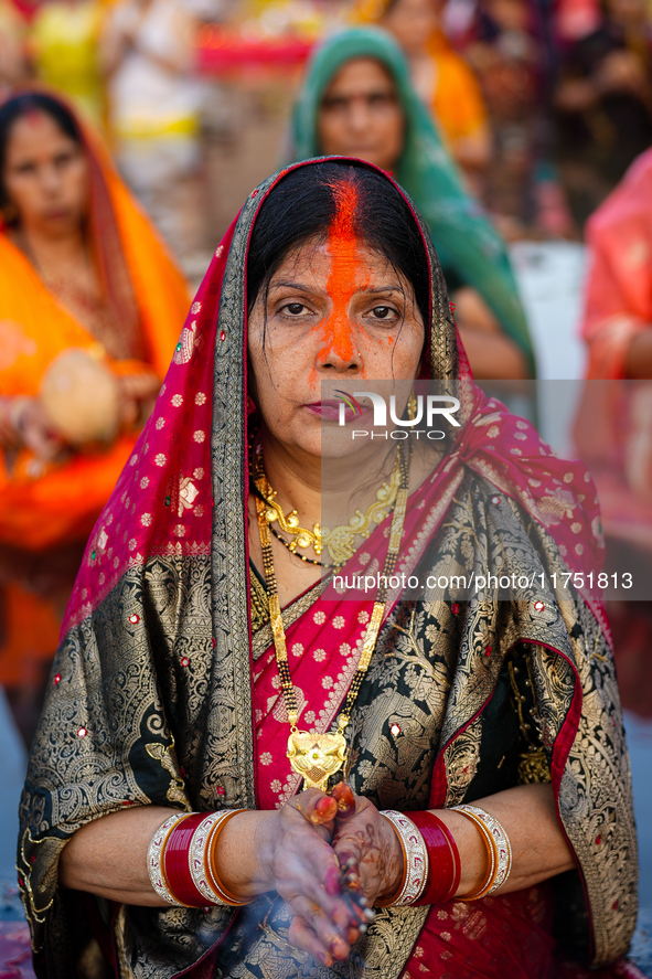 Hindu devotees perform rituals and offer prayers at sunset on the banks of the River Sabarmati during the Chhath Puja festival in Ahmedabad,...