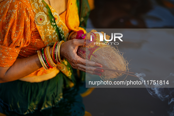 Hindu devotees perform rituals and offer prayers at sunset on the banks of the River Sabarmati during the Chhath Puja festival in Ahmedabad,...