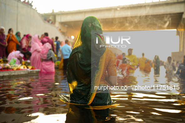 Hindu devotees perform rituals and offer prayers at sunset on the banks of the River Sabarmati during the Chhath Puja festival in Ahmedabad,...