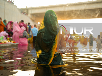 Hindu devotees perform rituals and offer prayers at sunset on the banks of the River Sabarmati during the Chhath Puja festival in Ahmedabad,...