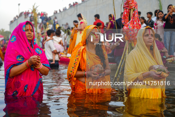 Hindu devotees perform rituals and offer prayers at sunset on the banks of the River Sabarmati during the Chhath Puja festival in Ahmedabad,...