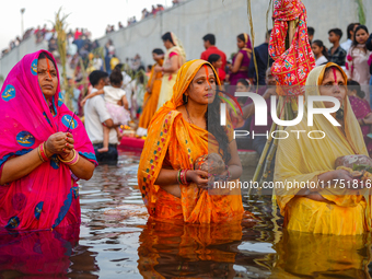 Hindu devotees perform rituals and offer prayers at sunset on the banks of the River Sabarmati during the Chhath Puja festival in Ahmedabad,...