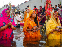 Hindu devotees perform rituals and offer prayers at sunset on the banks of the River Sabarmati during the Chhath Puja festival in Ahmedabad,...