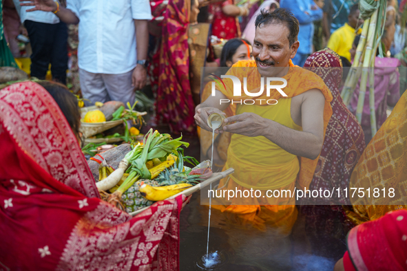 Hindu devotees perform rituals and offer prayers at sunset on the banks of the River Sabarmati during the Chhath Puja festival in Ahmedabad,...