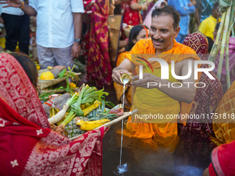 Hindu devotees perform rituals and offer prayers at sunset on the banks of the River Sabarmati during the Chhath Puja festival in Ahmedabad,...