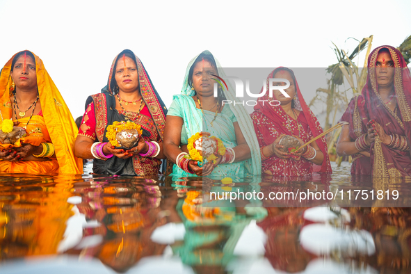 Hindu devotees perform rituals and offer prayers at sunset on the banks of the River Sabarmati during the Chhath Puja festival in Ahmedabad,...