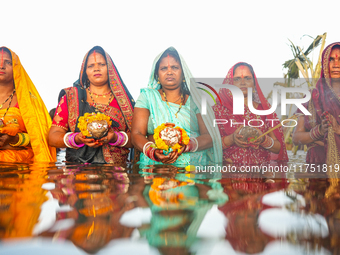 Hindu devotees perform rituals and offer prayers at sunset on the banks of the River Sabarmati during the Chhath Puja festival in Ahmedabad,...