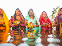 Hindu devotees perform rituals and offer prayers at sunset on the banks of the River Sabarmati during the Chhath Puja festival in Ahmedabad,...