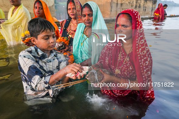 Hindu devotees perform rituals and offer prayers at sunset on the banks of the River Sabarmati during the Chhath Puja festival in Ahmedabad,...