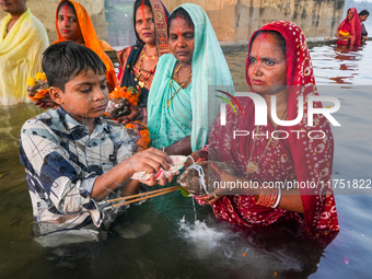 Hindu devotees perform rituals and offer prayers at sunset on the banks of the River Sabarmati during the Chhath Puja festival in Ahmedabad,...