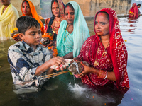 Hindu devotees perform rituals and offer prayers at sunset on the banks of the River Sabarmati during the Chhath Puja festival in Ahmedabad,...