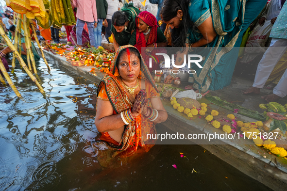 Hindu devotees perform rituals and offer prayers at sunset on the banks of the River Sabarmati during the Chhath Puja festival in Ahmedabad,...