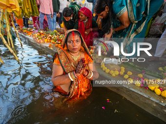 Hindu devotees perform rituals and offer prayers at sunset on the banks of the River Sabarmati during the Chhath Puja festival in Ahmedabad,...