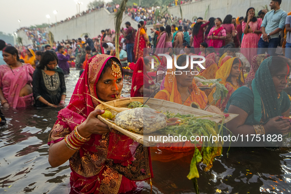 Hindu devotees perform rituals and offer prayers at sunset on the banks of the River Sabarmati during the Chhath Puja festival in Ahmedabad,...