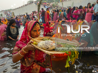 Hindu devotees perform rituals and offer prayers at sunset on the banks of the River Sabarmati during the Chhath Puja festival in Ahmedabad,...