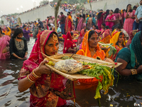 Hindu devotees perform rituals and offer prayers at sunset on the banks of the River Sabarmati during the Chhath Puja festival in Ahmedabad,...