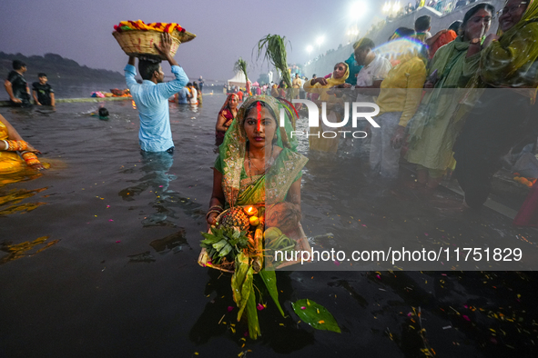 Hindu devotees perform rituals and offer prayers at sunset on the banks of the River Sabarmati during the Chhath Puja festival in Ahmedabad,...