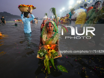 Hindu devotees perform rituals and offer prayers at sunset on the banks of the River Sabarmati during the Chhath Puja festival in Ahmedabad,...