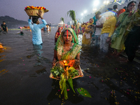 Hindu devotees perform rituals and offer prayers at sunset on the banks of the River Sabarmati during the Chhath Puja festival in Ahmedabad,...