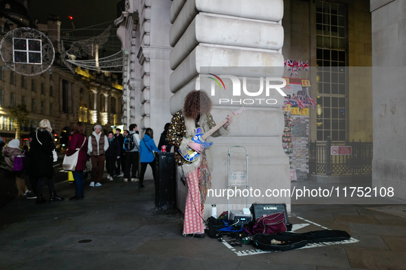 A street musician plays a guitar in Piccadilly Circus, London, on November 7, 2024. 