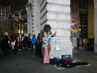 A street musician plays a guitar in Piccadilly Circus, London, on November 7, 2024. (