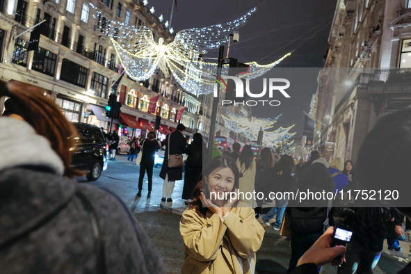 People gather and take photos of the Christmas lights in Regent Street, London, on November 7, 2024. 