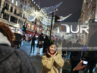 People gather and take photos of the Christmas lights in Regent Street, London, on November 7, 2024. (