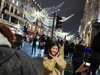 People gather and take photos of the Christmas lights in Regent Street, London, on November 7, 2024. (