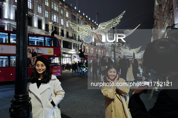 People gather and take photos of the Christmas lights in Regent Street, London, on November 7, 2024. 