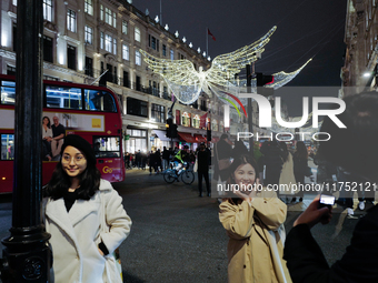 People gather and take photos of the Christmas lights in Regent Street, London, on November 7, 2024. (