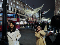 People gather and take photos of the Christmas lights in Regent Street, London, on November 7, 2024. (