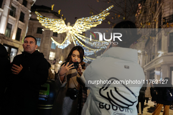 People take photos of the Christmas lights in Regent Street, London, on November 7, 2024. 