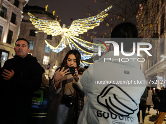 People take photos of the Christmas lights in Regent Street, London, on November 7, 2024. (