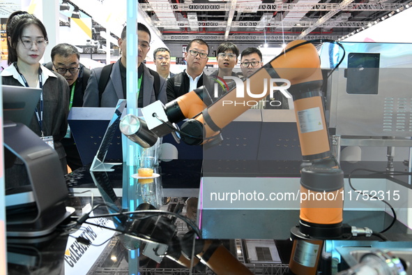 Visitors watch a ''bartending robot'' perform in front of the Siemens stand in the Technical Equipment Exhibition area of the 7th China Inte...