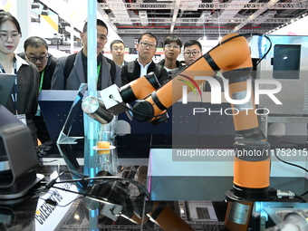 Visitors watch a ''bartending robot'' perform in front of the Siemens stand in the Technical Equipment Exhibition area of the 7th China Inte...