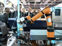 Visitors watch a ''bartending robot'' perform in front of the Siemens stand in the Technical Equipment Exhibition area of the 7th China Inte...