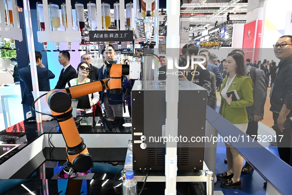 Visitors watch a ''bartending robot'' perform in front of the Siemens stand in the Technical Equipment Exhibition area of the 7th China Inte...