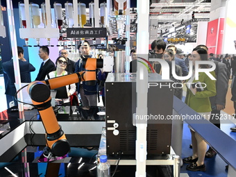 Visitors watch a ''bartending robot'' perform in front of the Siemens stand in the Technical Equipment Exhibition area of the 7th China Inte...