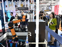 Visitors watch a ''bartending robot'' perform in front of the Siemens stand in the Technical Equipment Exhibition area of the 7th China Inte...