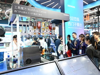 Visitors watch a ''bartending robot'' perform in front of the Siemens stand in the Technical Equipment Exhibition area of the 7th China Inte...