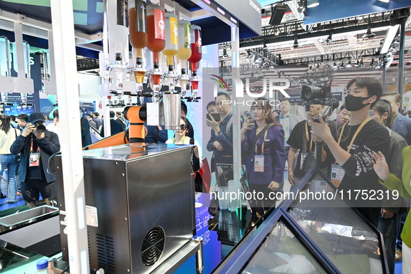 Visitors watch a ''bartending robot'' perform in front of the Siemens stand in the Technical Equipment Exhibition area of the 7th China Inte...