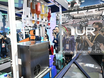 Visitors watch a ''bartending robot'' perform in front of the Siemens stand in the Technical Equipment Exhibition area of the 7th China Inte...