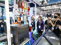 Visitors watch a ''bartending robot'' perform in front of the Siemens stand in the Technical Equipment Exhibition area of the 7th China Inte...