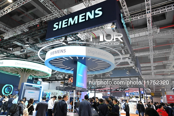 Visitors watch a ''bartending robot'' perform in front of the Siemens stand in the Technical Equipment Exhibition area of the 7th China Inte...