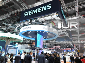 Visitors watch a ''bartending robot'' perform in front of the Siemens stand in the Technical Equipment Exhibition area of the 7th China Inte...