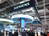 Visitors watch a ''bartending robot'' perform in front of the Siemens stand in the Technical Equipment Exhibition area of the 7th China Inte...