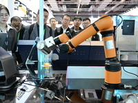 Visitors watch a ''bartending robot'' perform in front of the Siemens stand in the Technical Equipment Exhibition area of the 7th China Inte...