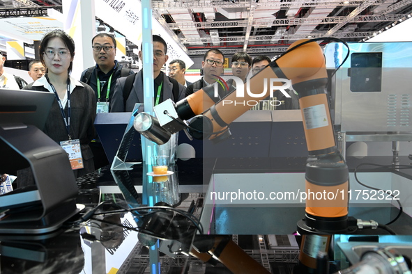 Visitors watch a ''bartending robot'' perform in front of the Siemens stand in the Technical Equipment Exhibition area of the 7th China Inte...