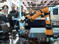 Visitors watch a ''bartending robot'' perform in front of the Siemens stand in the Technical Equipment Exhibition area of the 7th China Inte...